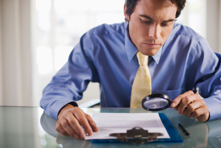 Businessman with magnifying glass reading small print