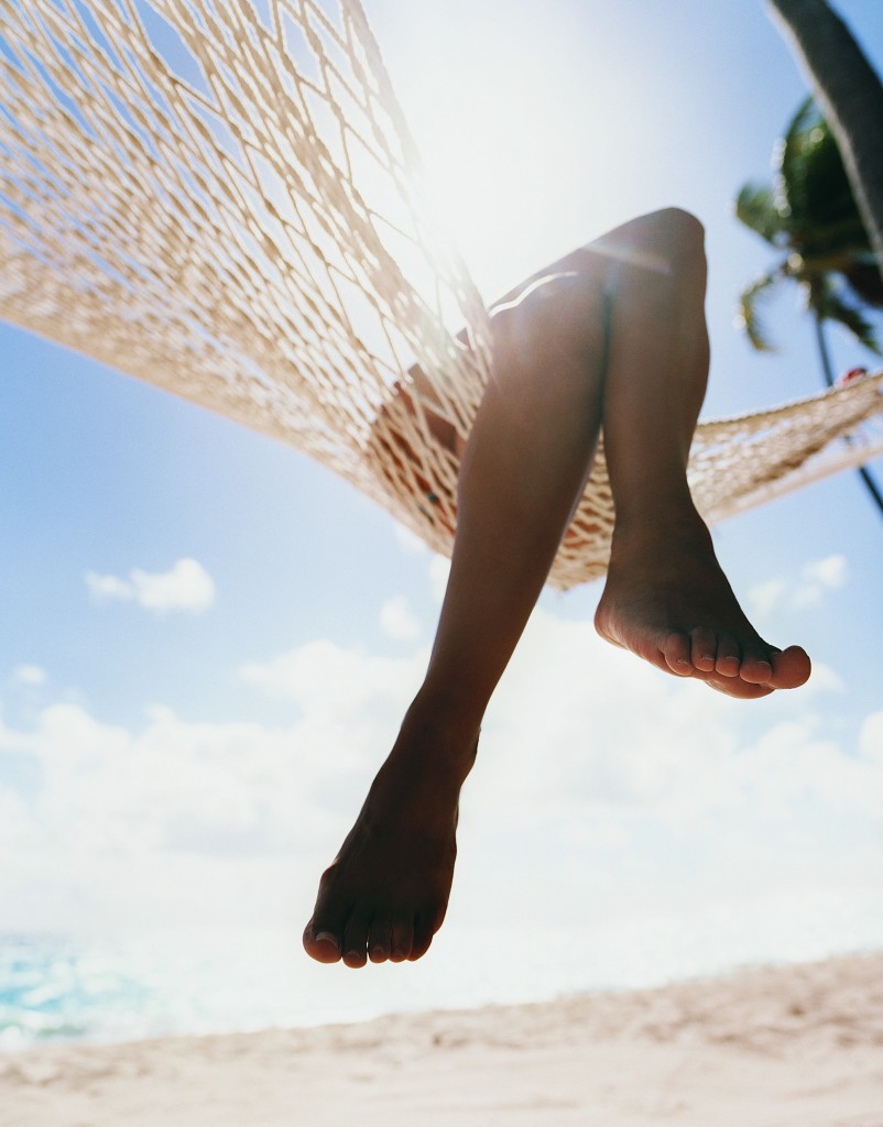 Close up of a Person's Crossed Legs Hanging at the Edge of a Hammock on a Beach
