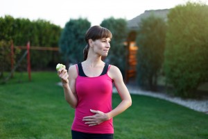 Hungry sporty woman with apple