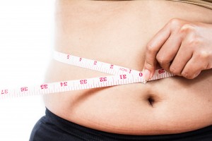 Woman measuring waist line with tape measure