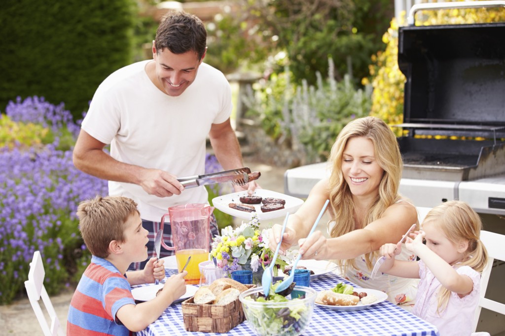 Family Enjoying Outdoor Barbeque In Garden