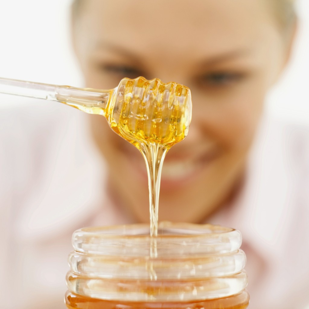 close-up of a young woman holding a honey dipper