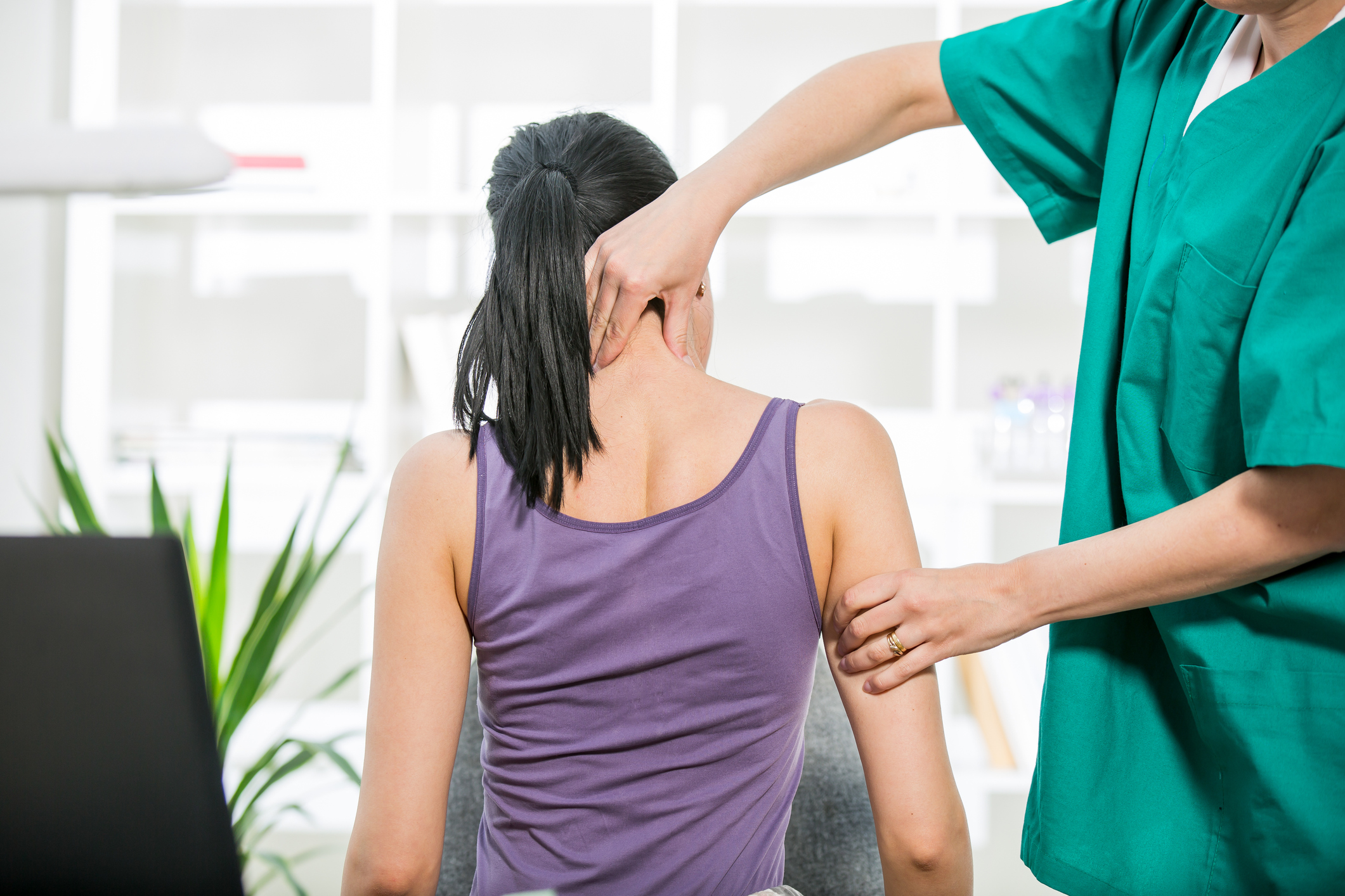 Chiropractor stretches female patient neck muscles